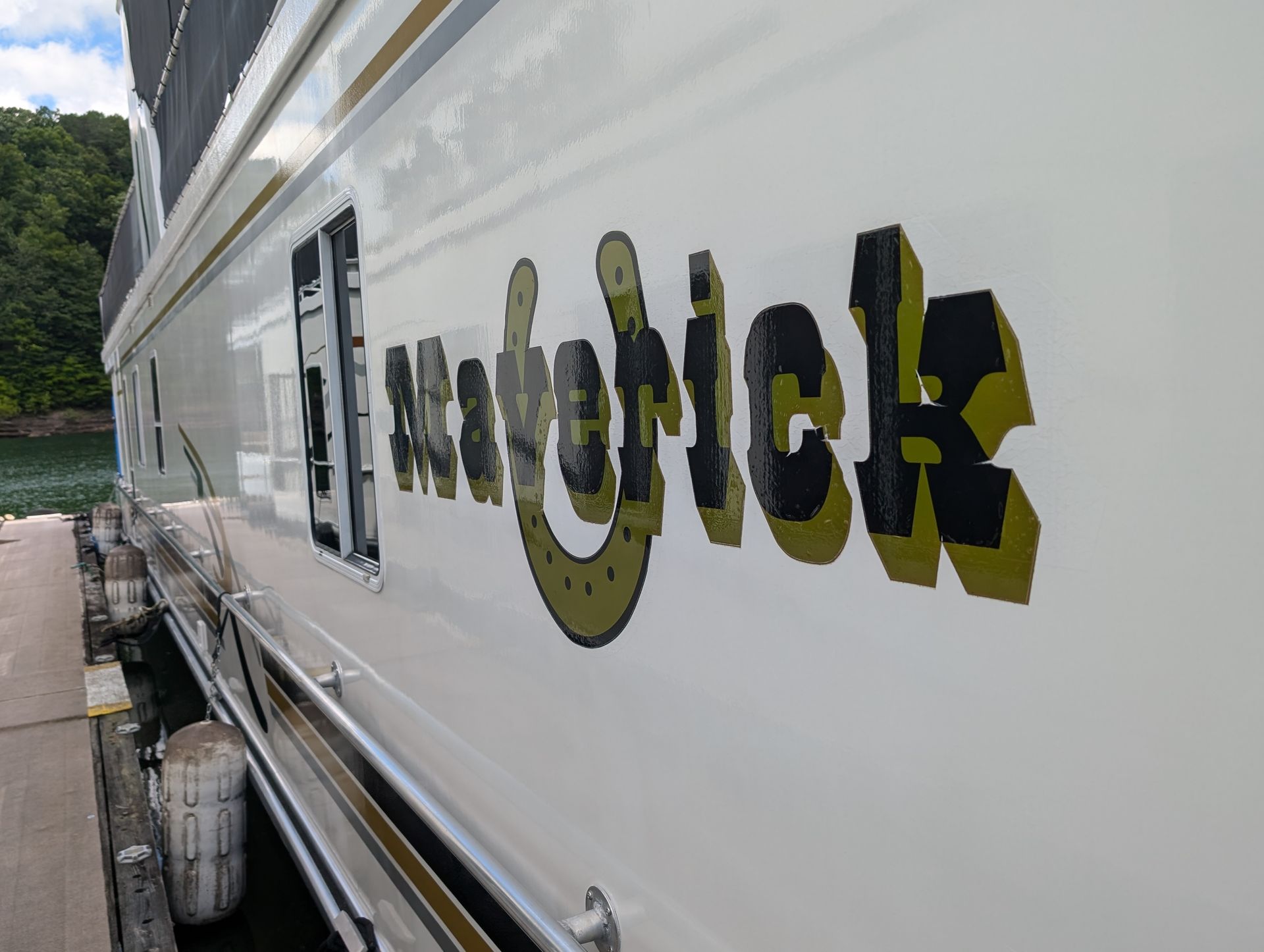 Camper trailer side with colorful graffiti-style lettering near a walkway and trees