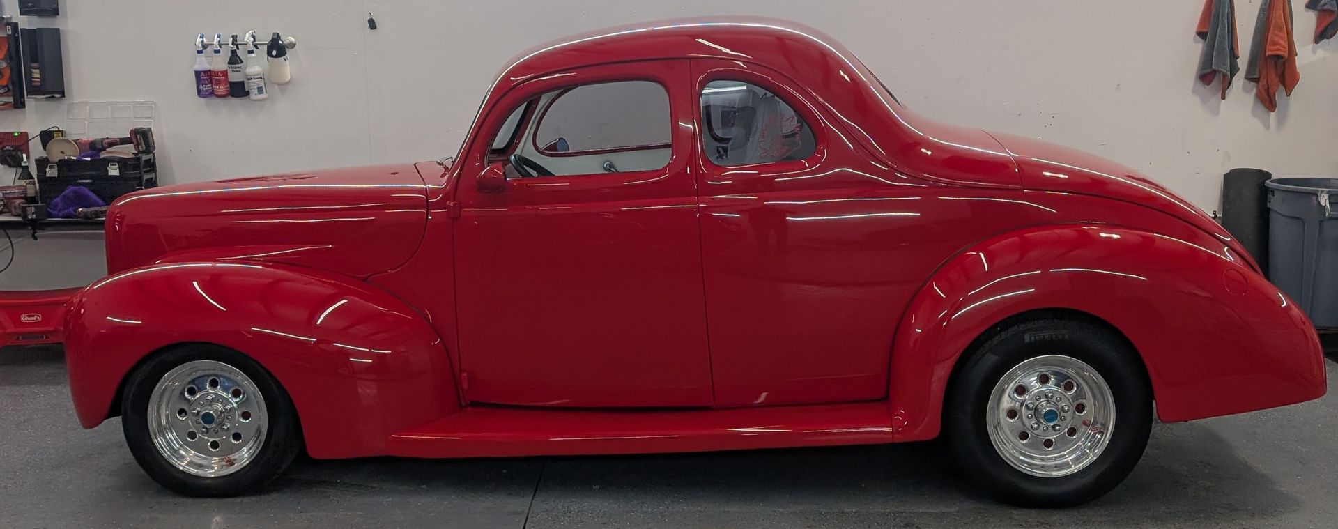 Side view of a shiny red vintage coupe in a garage or showroom
