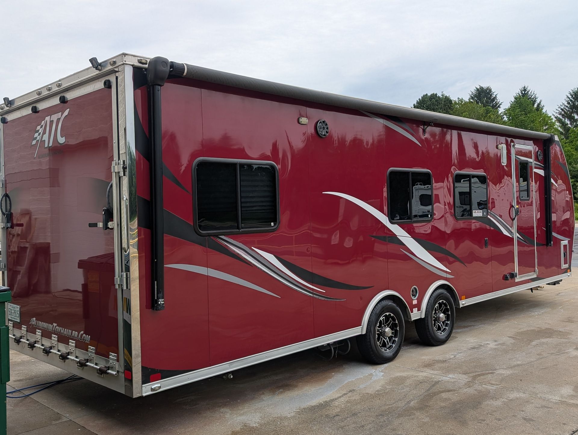 Red enclosed trailer with black windows, silver swoosh graphics, and dual axles parked outdoors