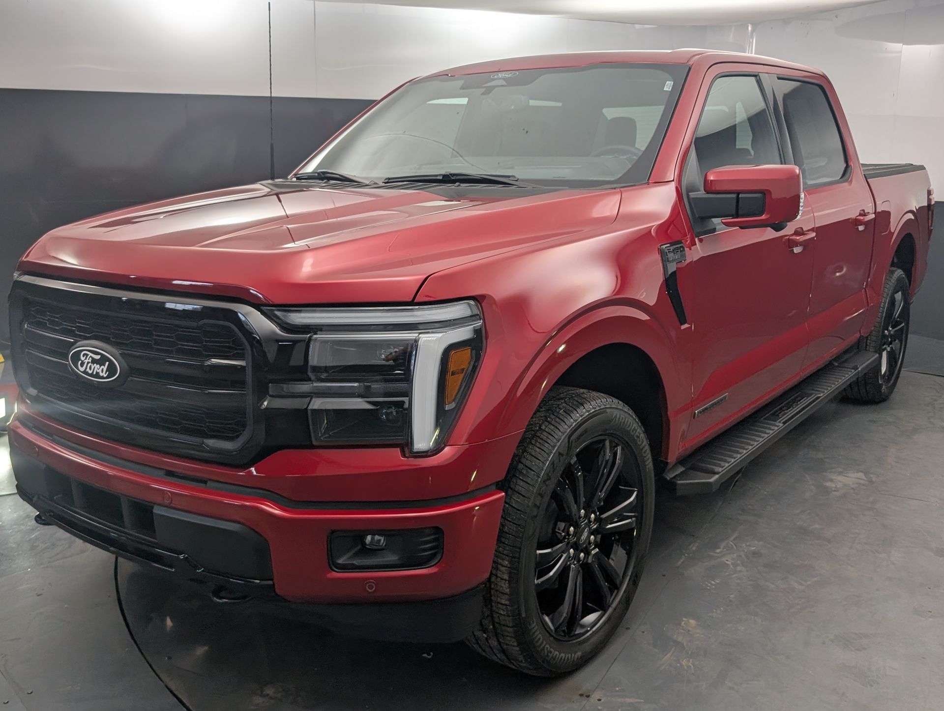 Red Ford pickup truck in a showroom, angled front view, with black grille and wheels.