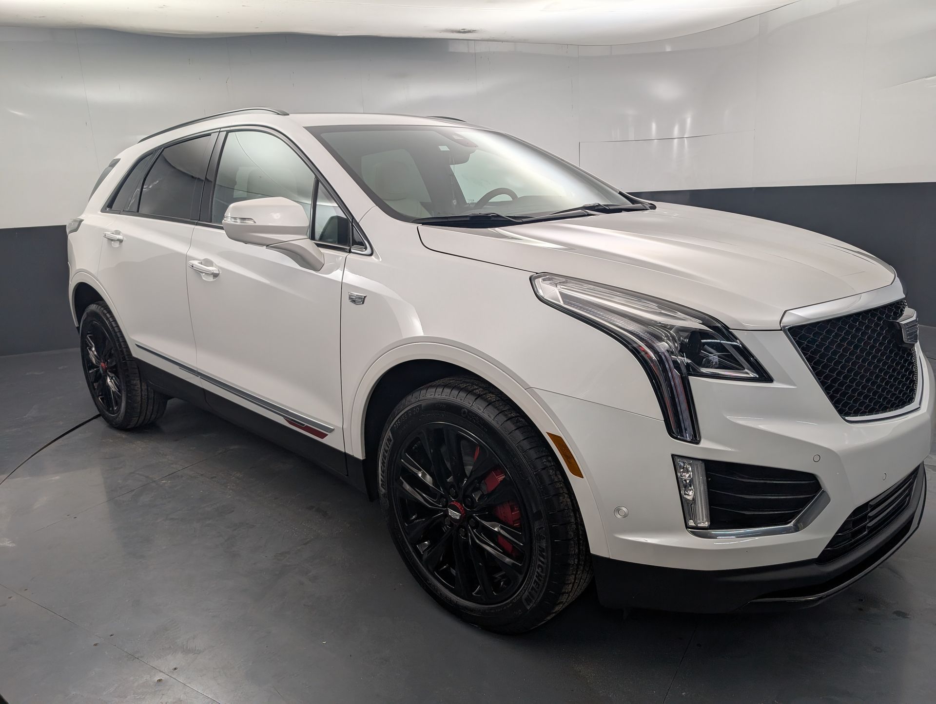 White SUV with black wheels parked indoors in a showroom-like garage