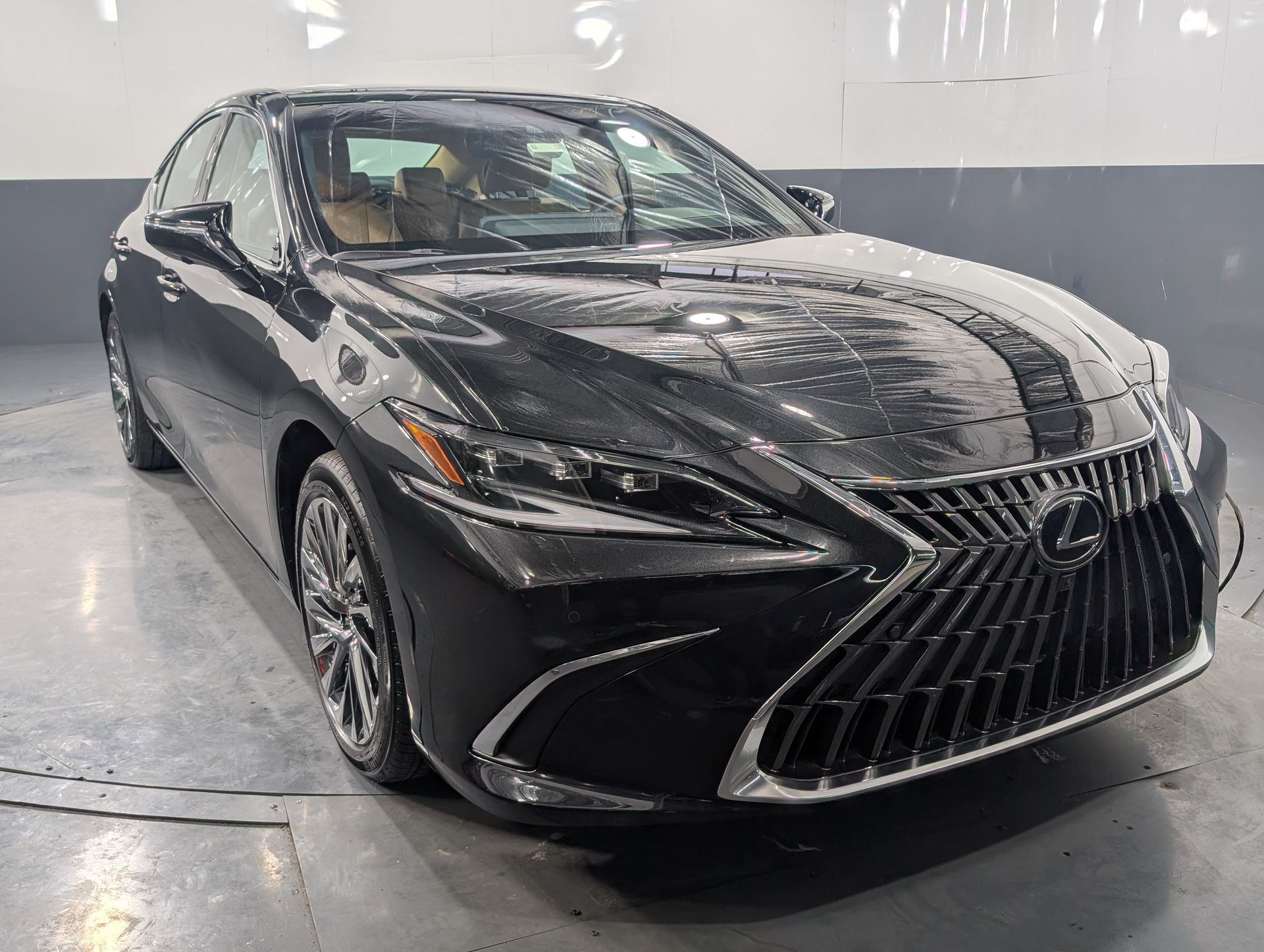 Black Lexus sedan parked indoors on a wet floor, front three-quarter view
