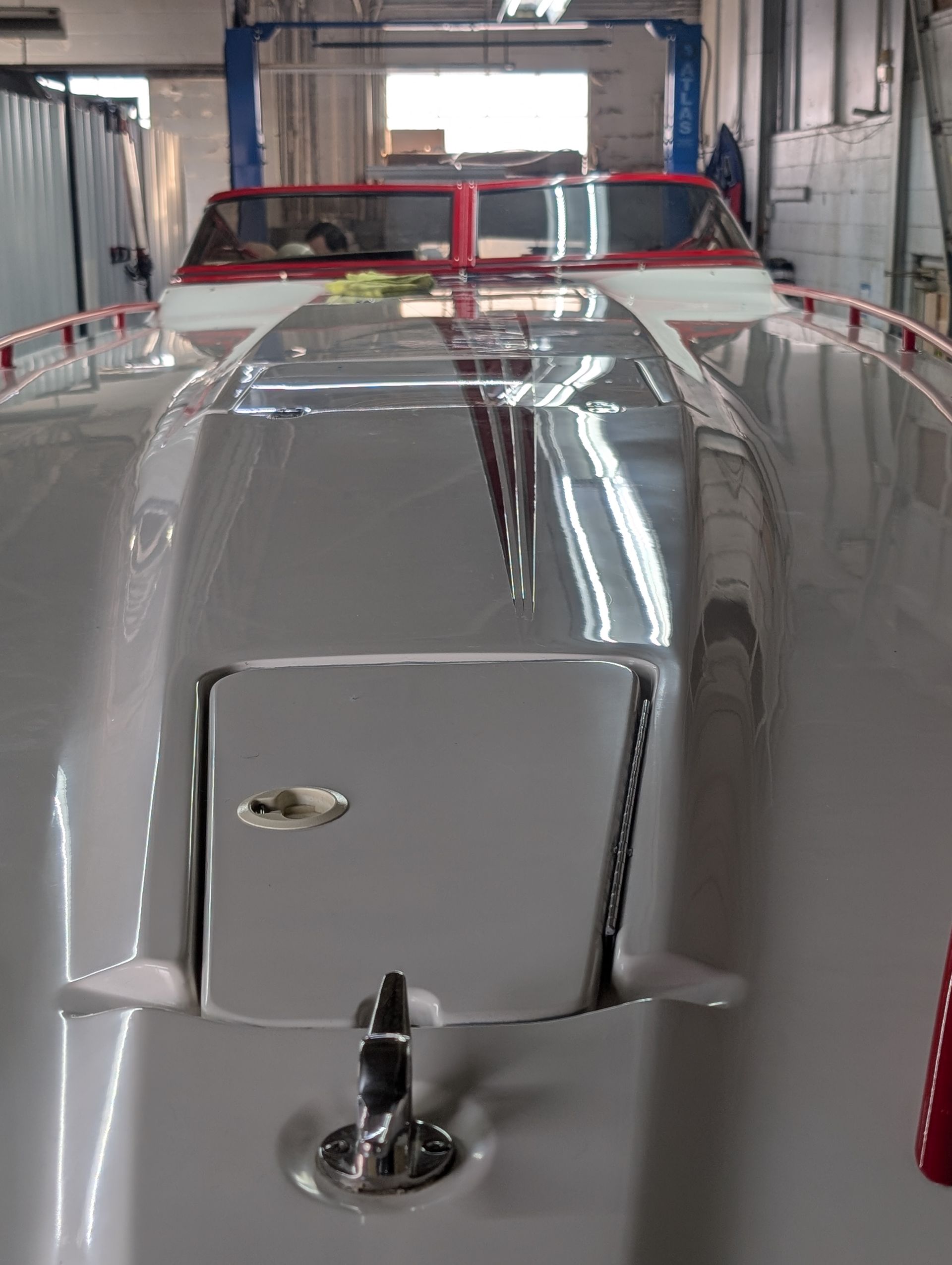 Silver vintage convertible in a garage, front view with a red windshield frame and chrome details