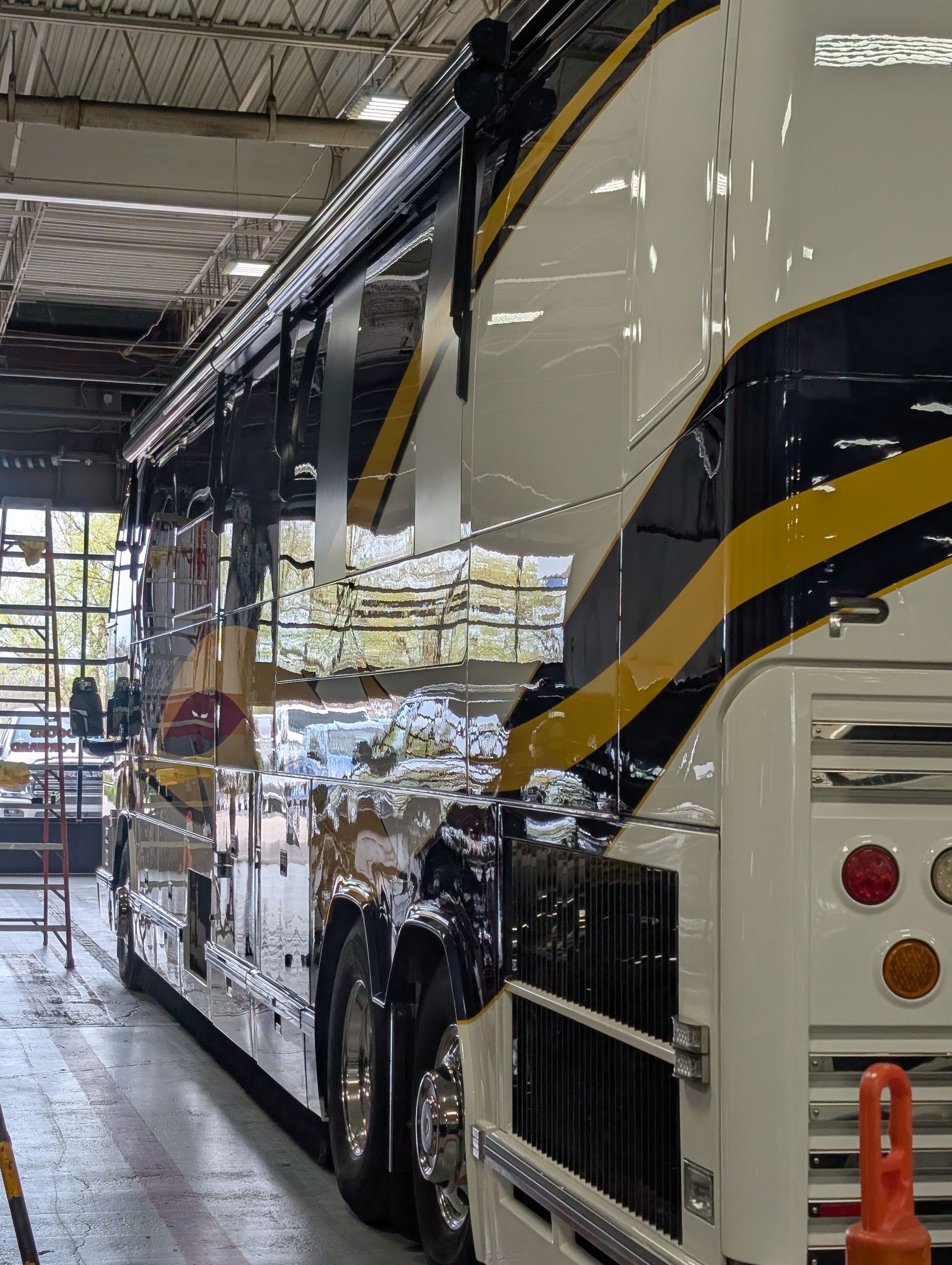 White and black luxury coach bus parked inside a maintenance garage