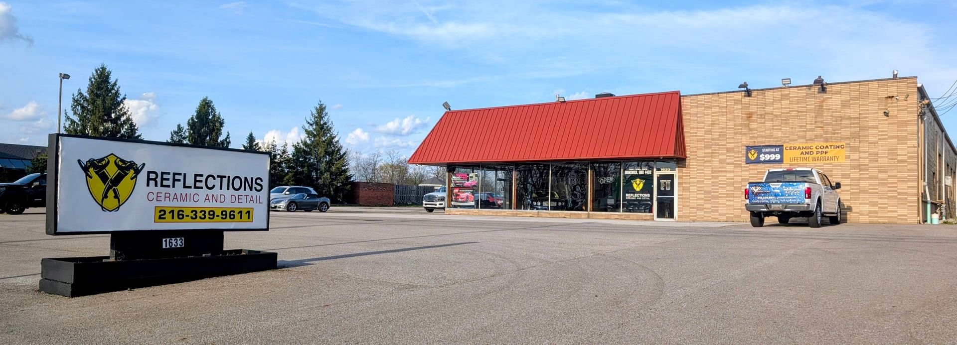 Northwoods-themed store with a red roof, roadside sign, and parked blue truck in front