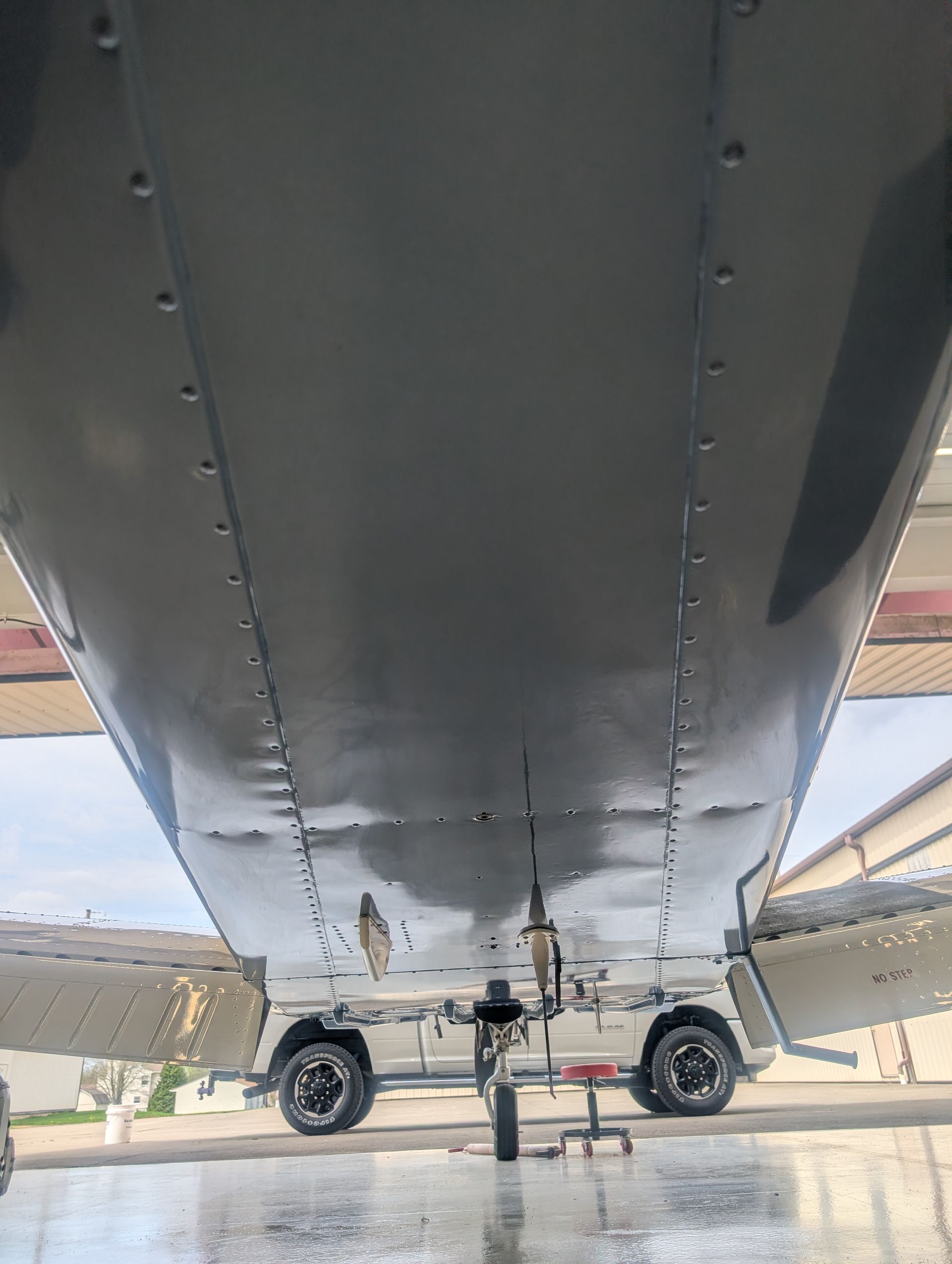 Underside view of a small airplane on a tarmac, with landing gear and propeller visible.