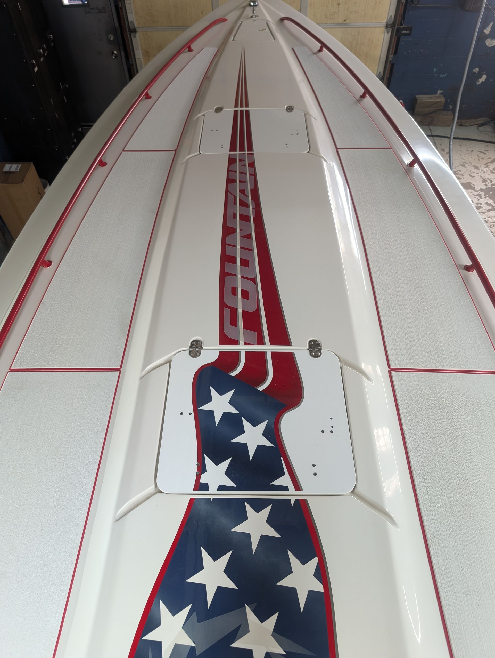 White surfboard with red stripes and blue stars on a workshop floor