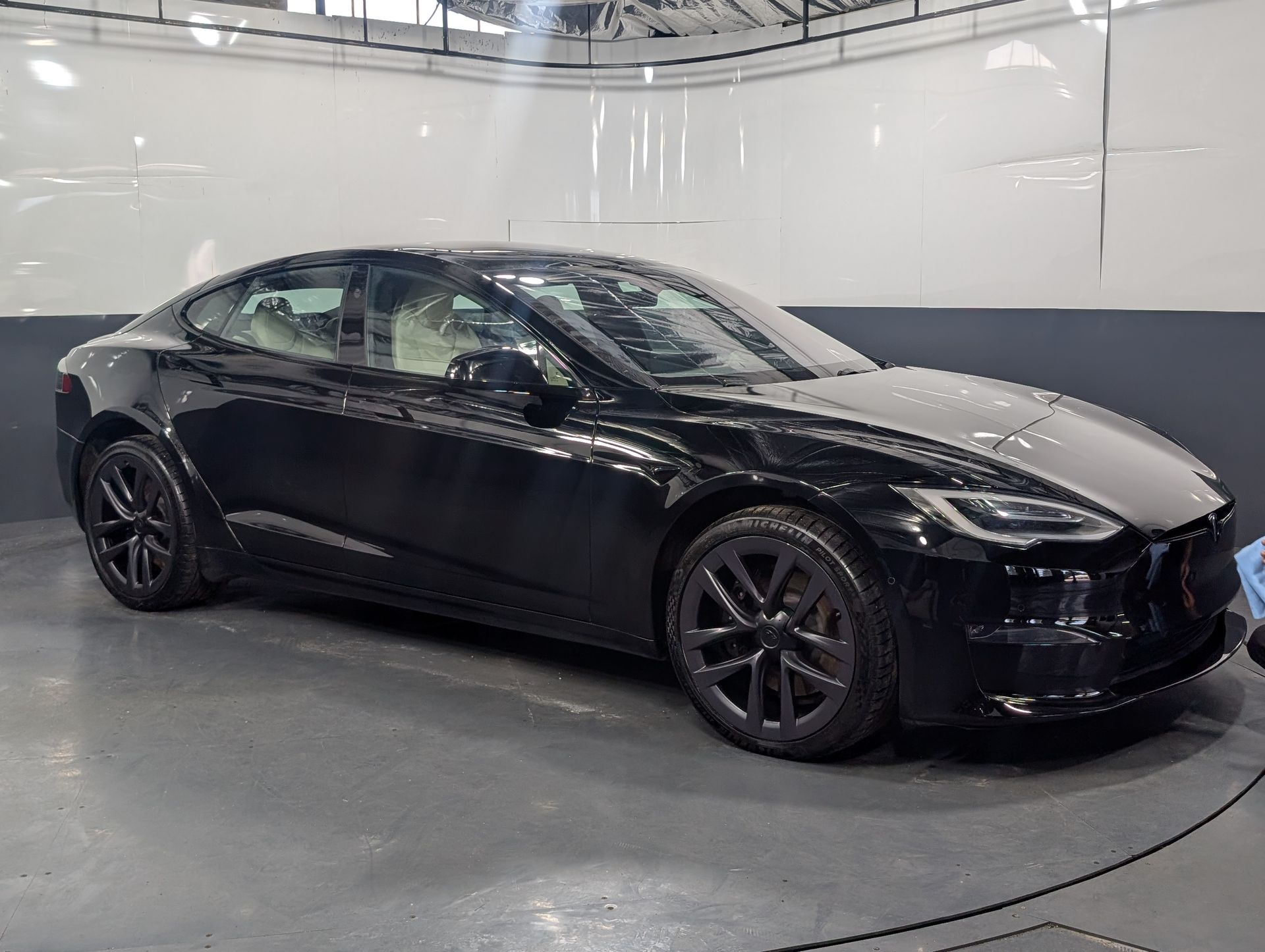 Black sports coupe parked indoors in a showroom, viewed from the side.