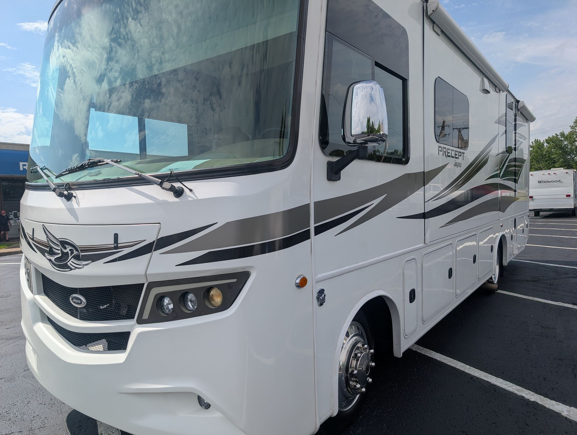 White motorhome RV parked in a lot, front view with gray and black stripes