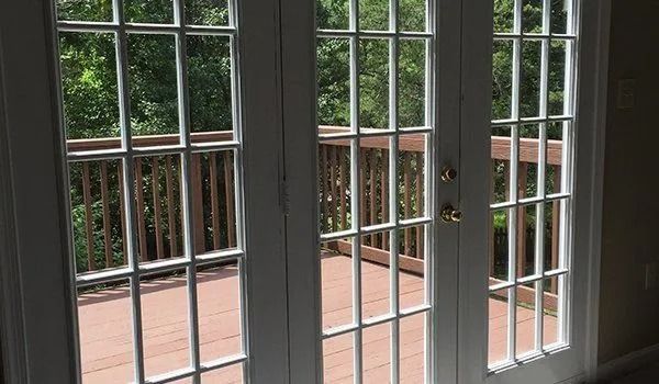 White French doors opening to a deck with a wooded view.