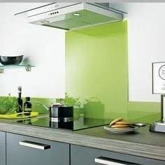 Modern kitchen with gray cabinets, lime green backsplash, stainless steel range hood, and countertop items.