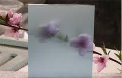 Frosted glass with blurred purple flowers and pink blooms nearby.