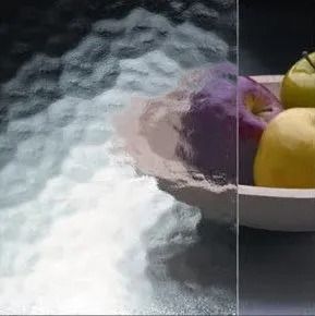 Textured glass pane showing fruit in a bowl, the reflection of the glass distorts the objects.
