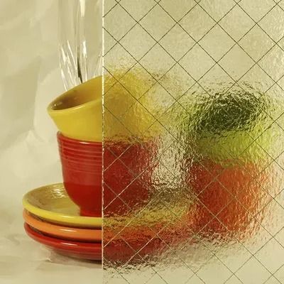 Glass pane with grid pattern obscuring colorful bowls and fruit.