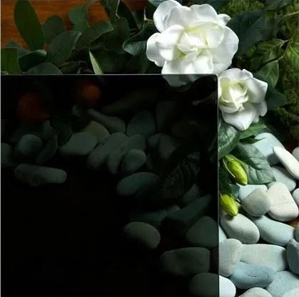 White gardenias and rocks reflected in black glass.