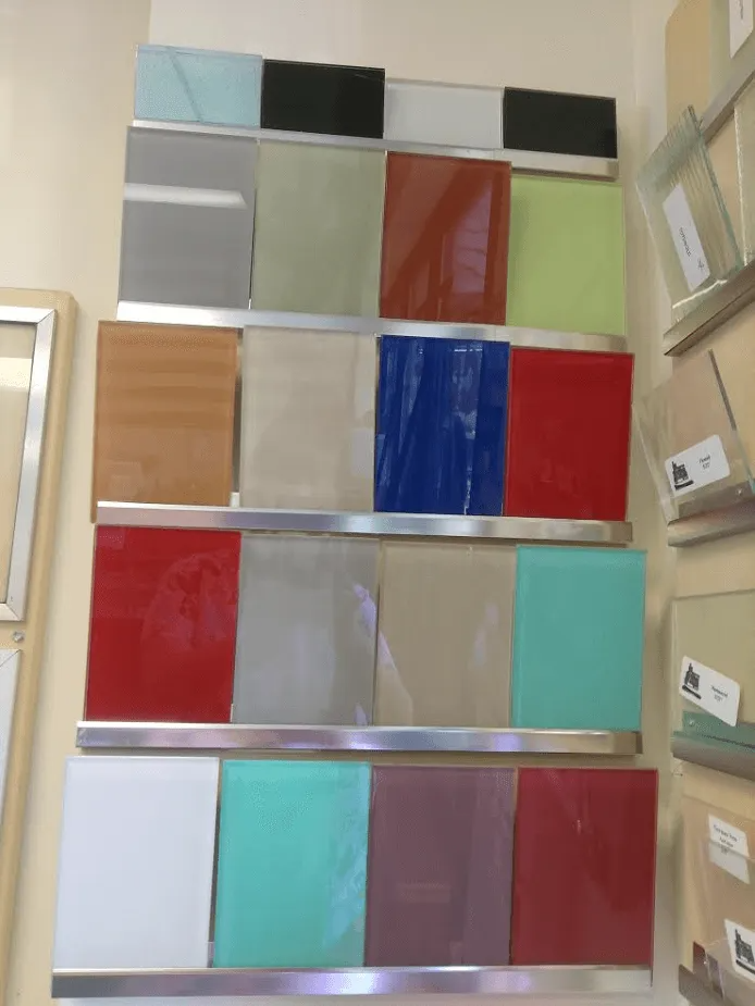 Color glass samples displayed on a wall, showcasing various hues like red, green, blue, and beige.