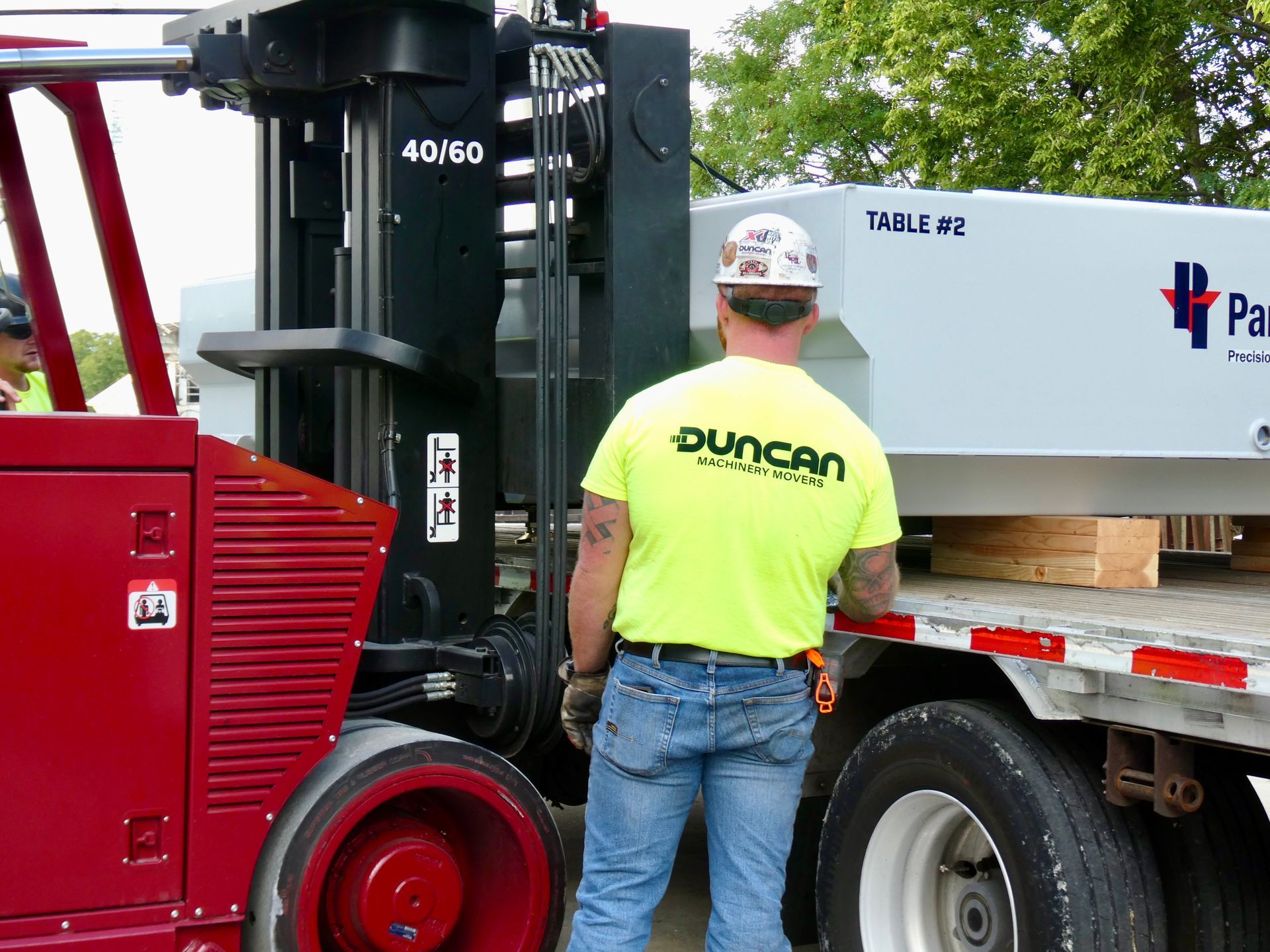 Worker in neon yellow shirt unloading a large white crate beside a red forklift at a warehouse dock