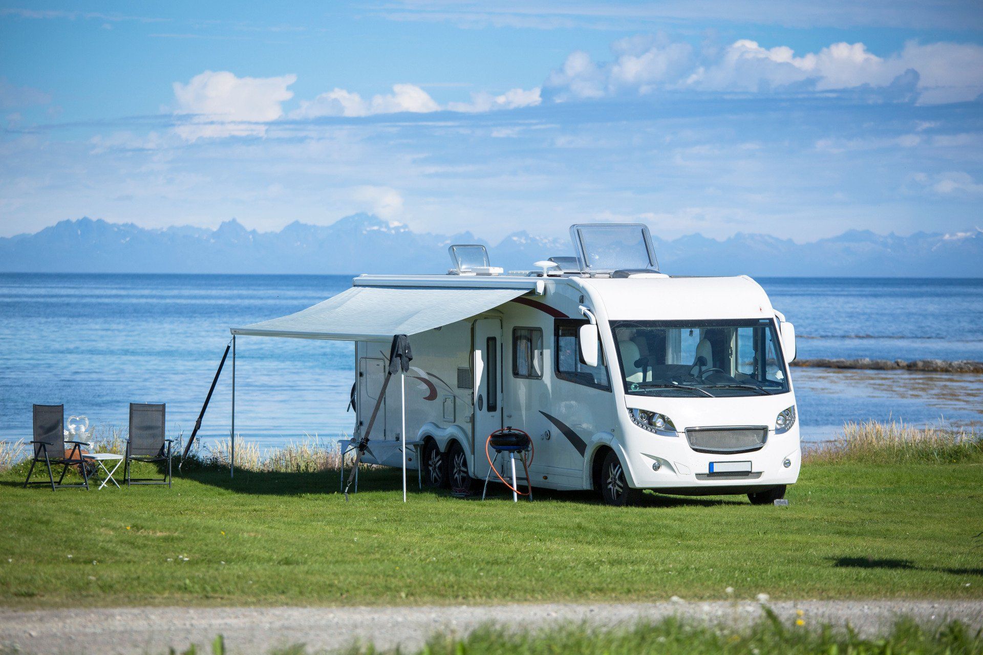 A rv is parked in a grassy field next to the ocean.