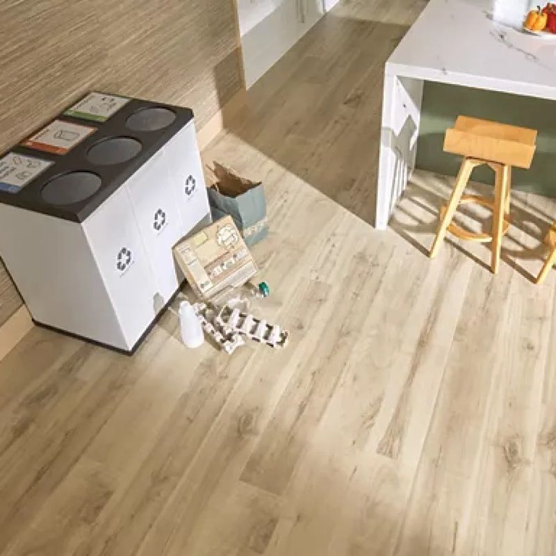 Small room with a white cabinet, stools, a table, and cardboard boxes on a light wood floor.