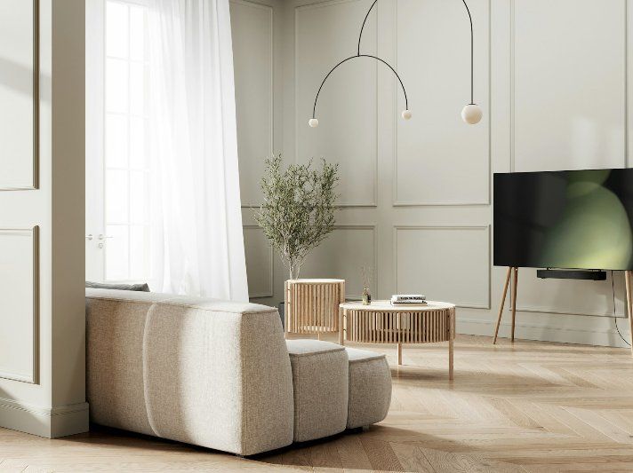 Minimalist living room with beige sofa, wooden tables, indoor plant, and large window with sheer curtains