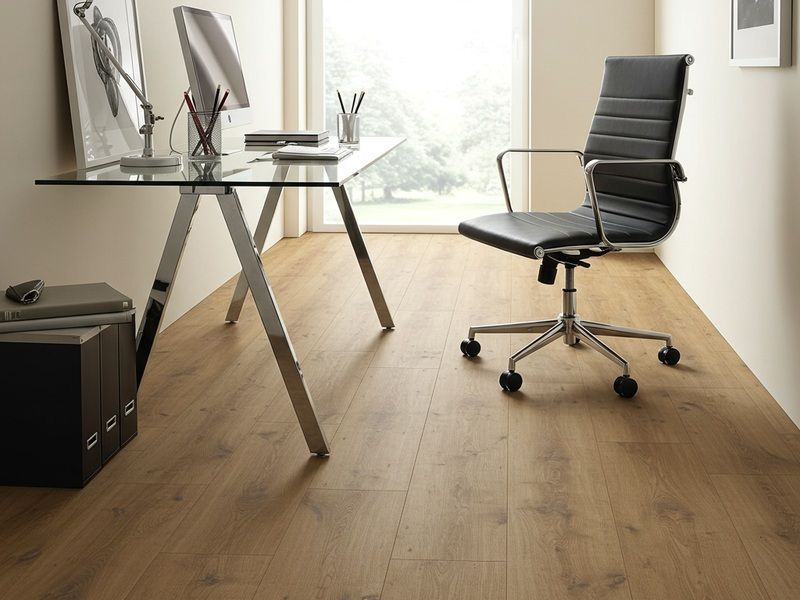 Modern home office with glass desk, black chair, and wood floor near a bright window