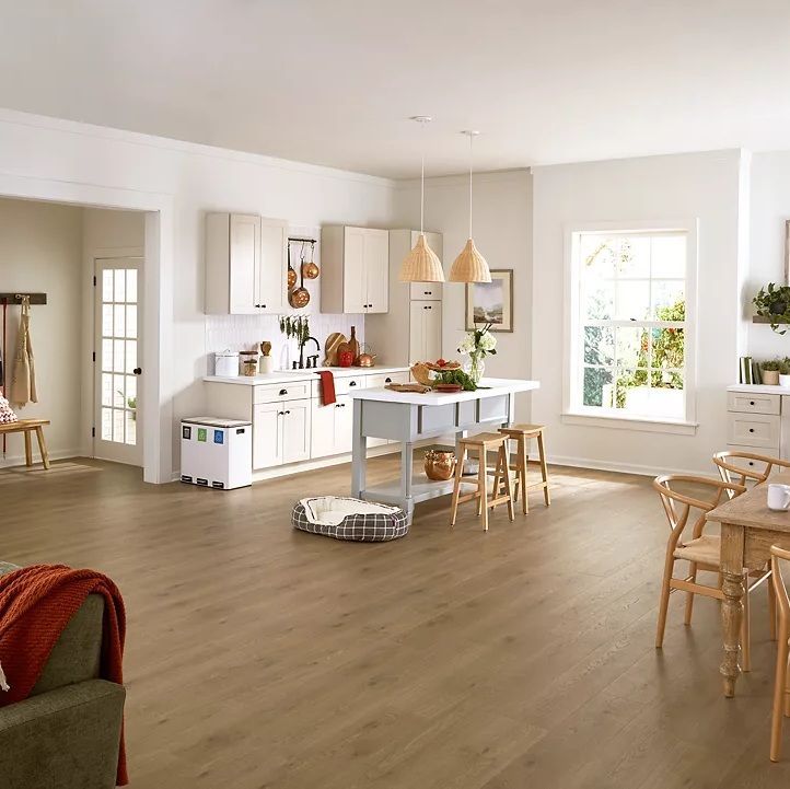 Bright, airy kitchen with white cabinets, island, wood floors, and wicker chairs in a modern open-plan room