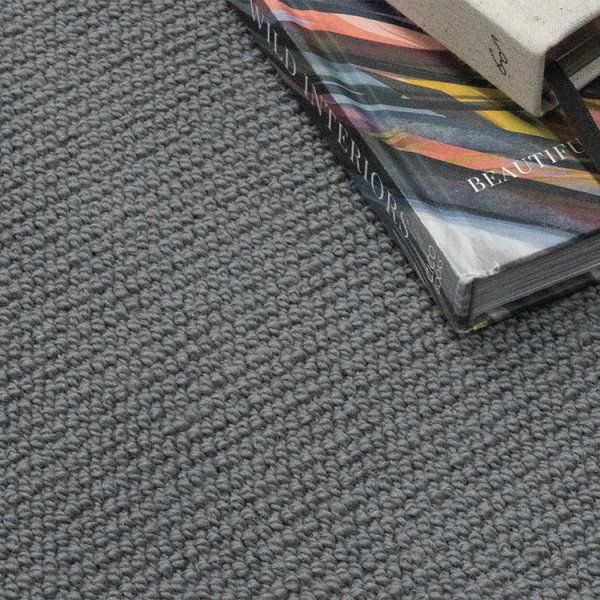 Gray textured carpet with two stacked books in the upper right corner.