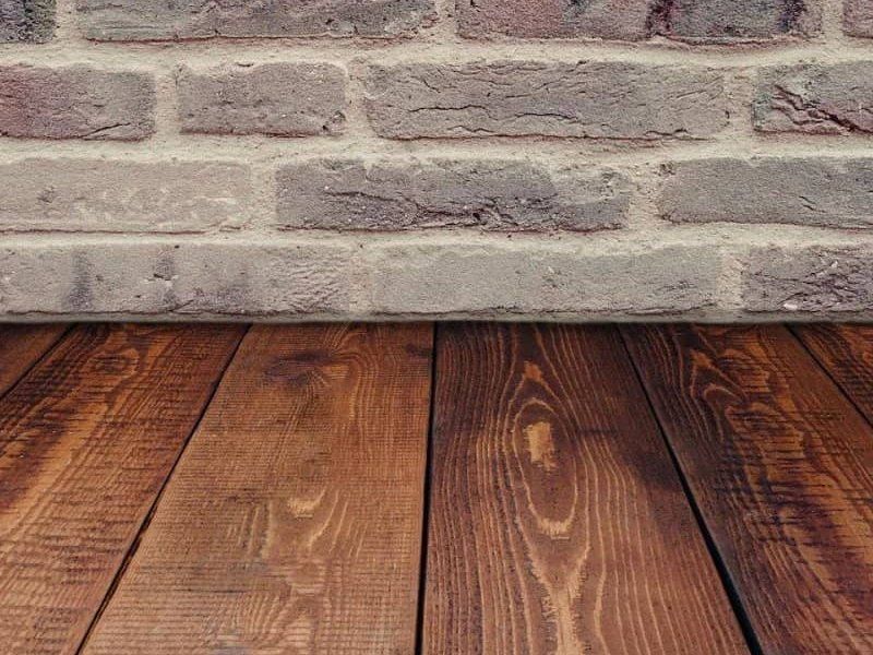 Wooden floorboards in front of a white brick wall background
