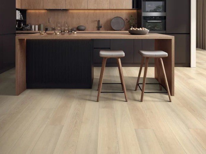 Modern kitchen with wood cabinets, island, two stools, and light wood flooring