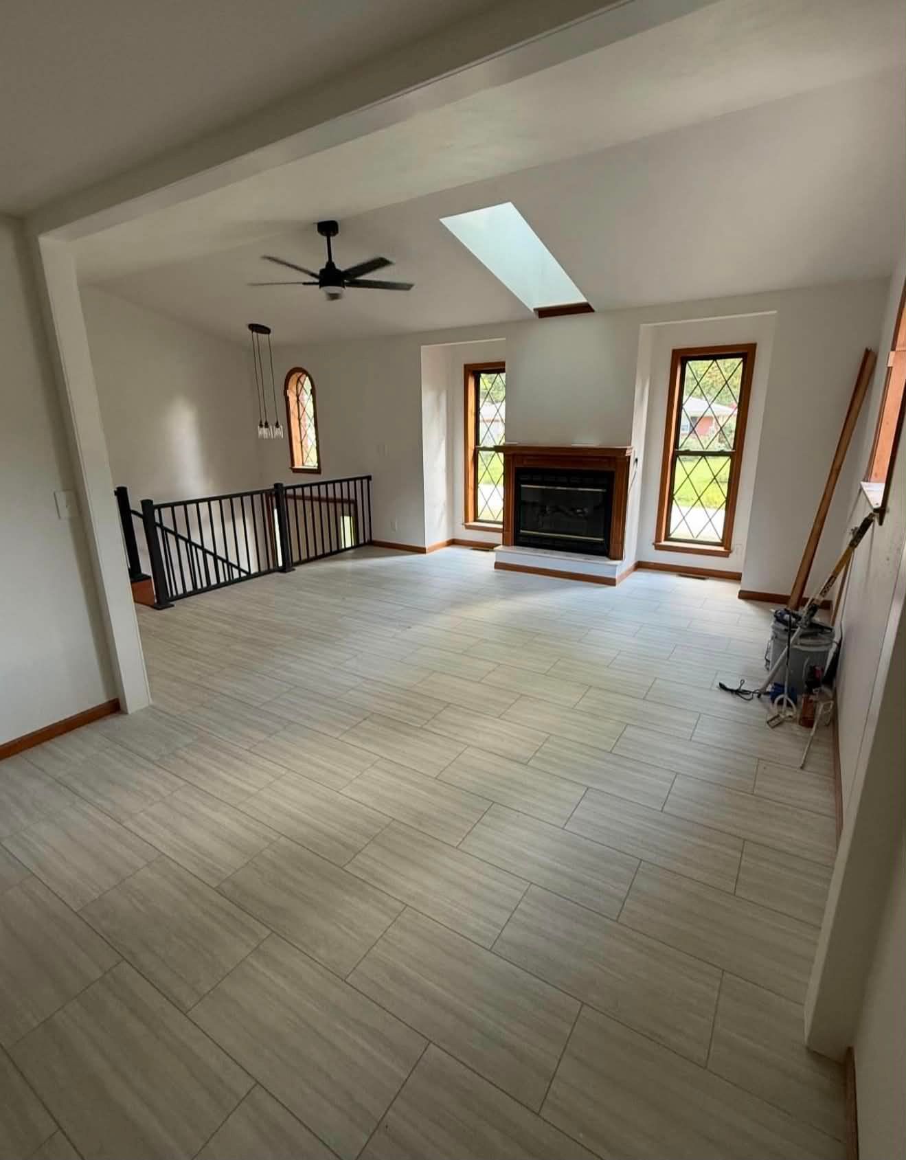 Spacious empty living room with vaulted ceiling, skylight, fireplace, and balcony railing.