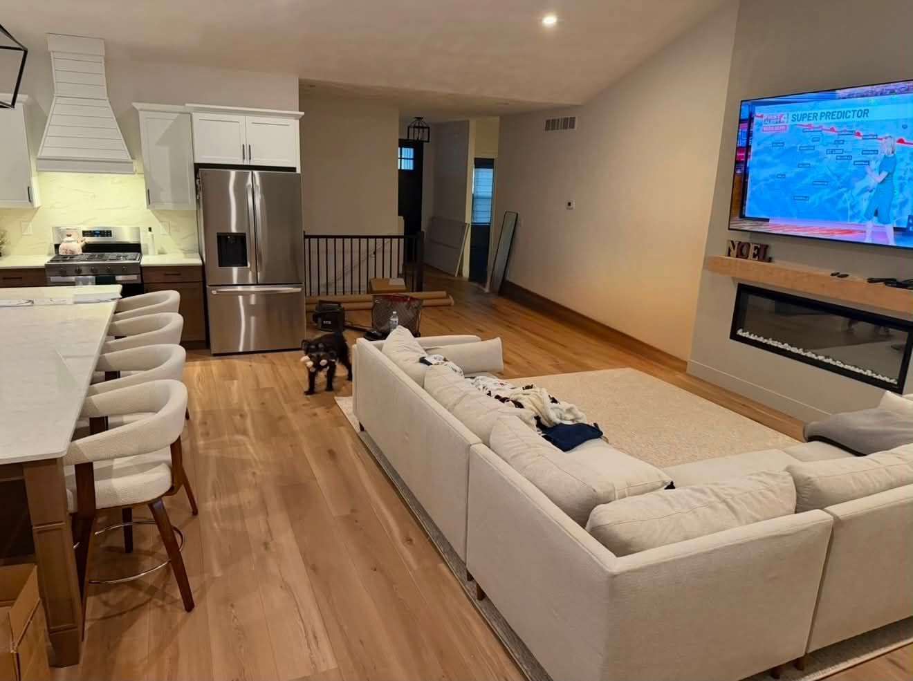 Large open room with gray-brown wood flooring, a floor buffer on the left, and carpeted stairs on the right