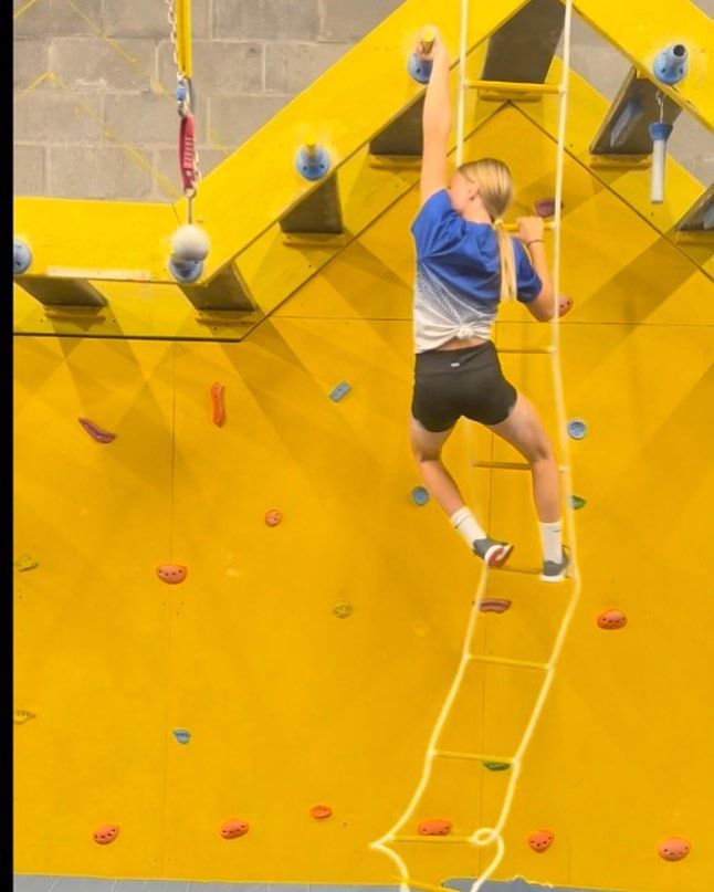A man is climbing up a ladder on a yellow wall