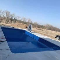 A large blue swimming pool is sitting on top of a concrete deck.