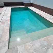 There is a swimming pool with stairs leading to it.