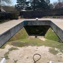 An empty swimming pool with a hose attached to it.