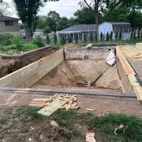 A swimming pool is being built in the backyard of a house.