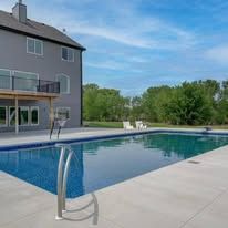 There is a large swimming pool in front of a house.