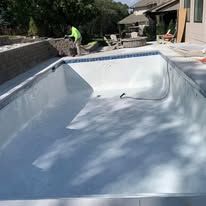 A man is working on a swimming pool in a backyard.