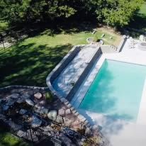 An aerial view of a large swimming pool surrounded by trees and grass.