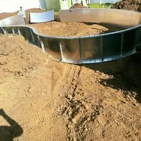 A metal swimming pool is sitting on top of a pile of dirt.