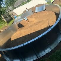 A large swimming pool is being built in a backyard.