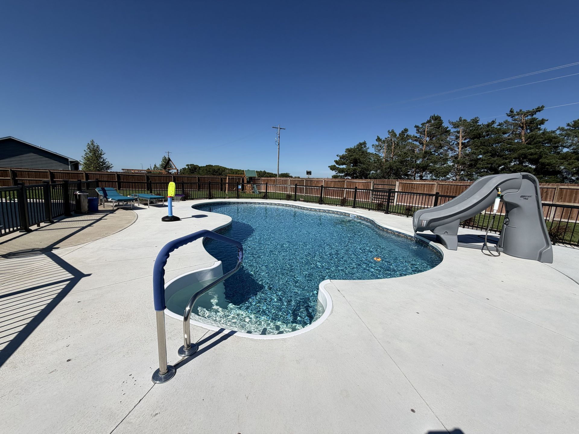 Outdoor swimming pool with a curved slide, blue water, and a clear sky