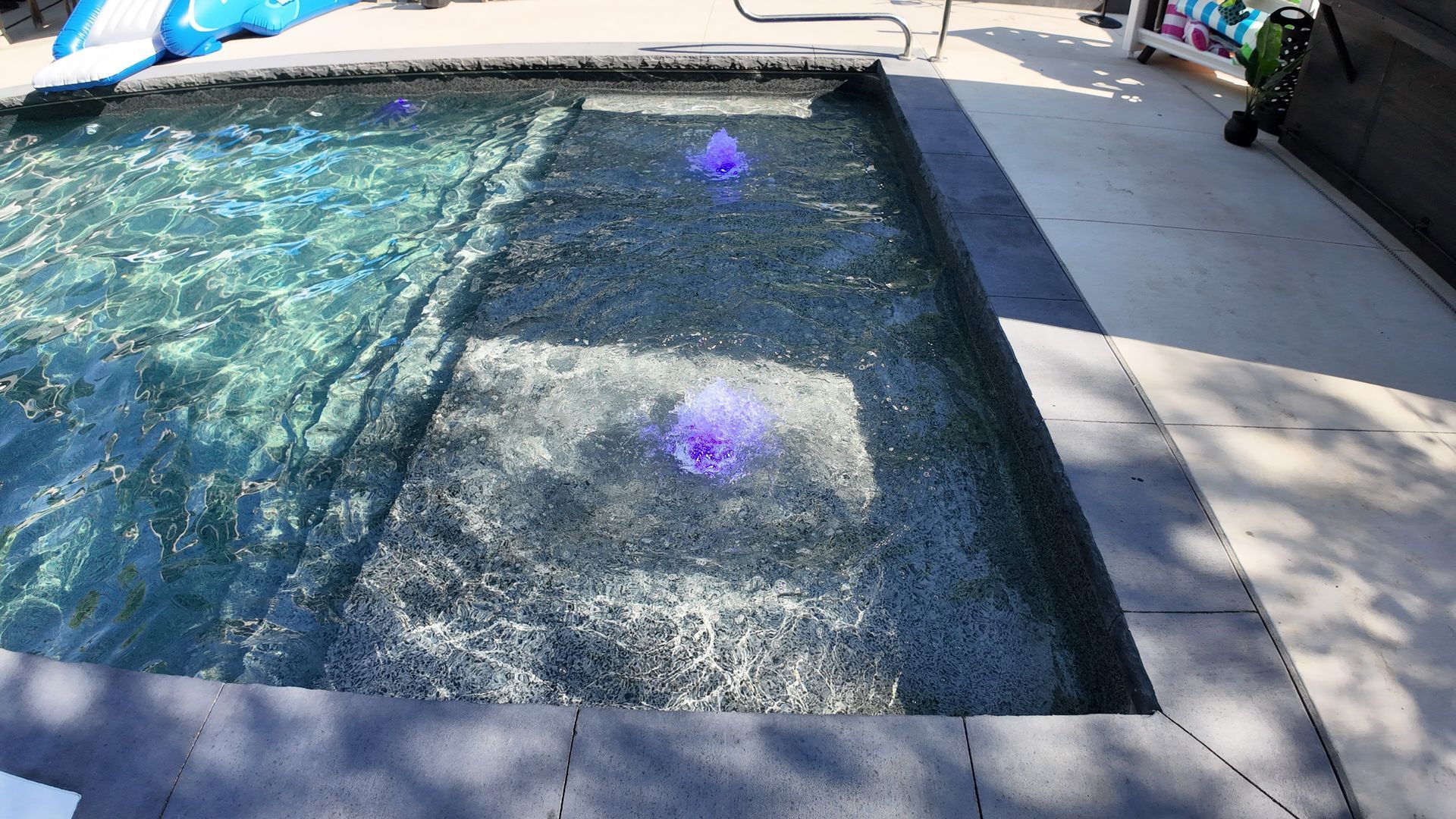 Backyard swimming pool with rippling blue water and sunlight reflecting across the surface