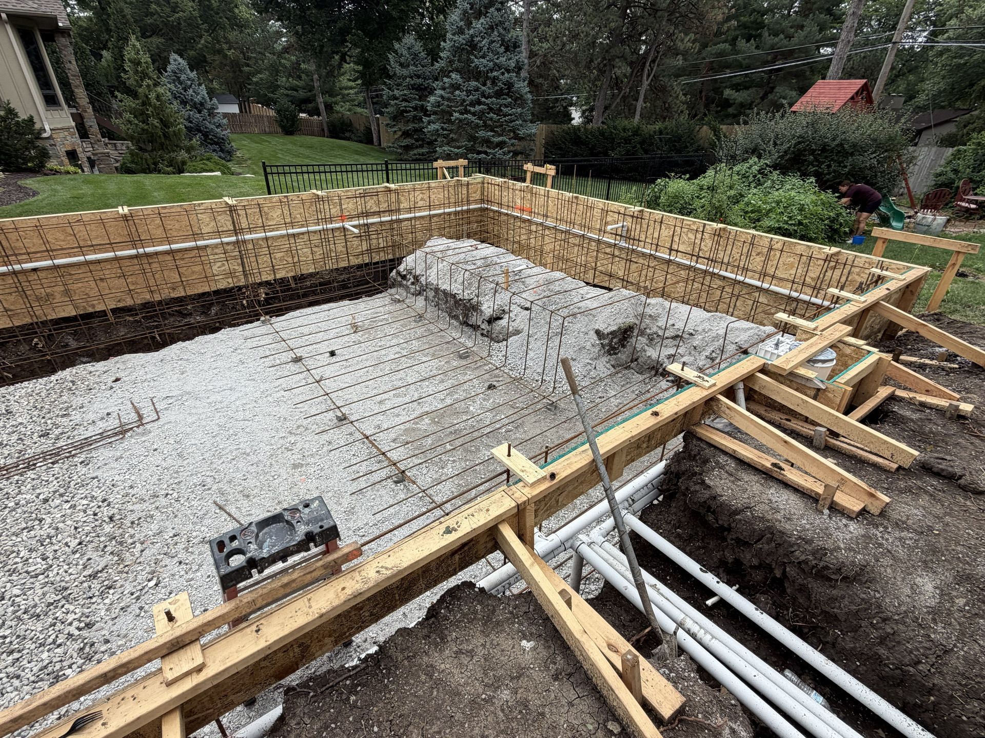 Concrete foundation under construction with wooden formwork and rebar in a grassy residential yard