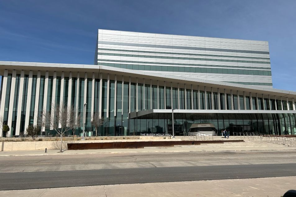 A large building with a lot of windows and a blue sky in the background.