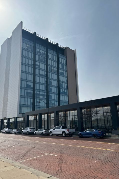 A large building with a lot of windows and cars parked in front of it.
