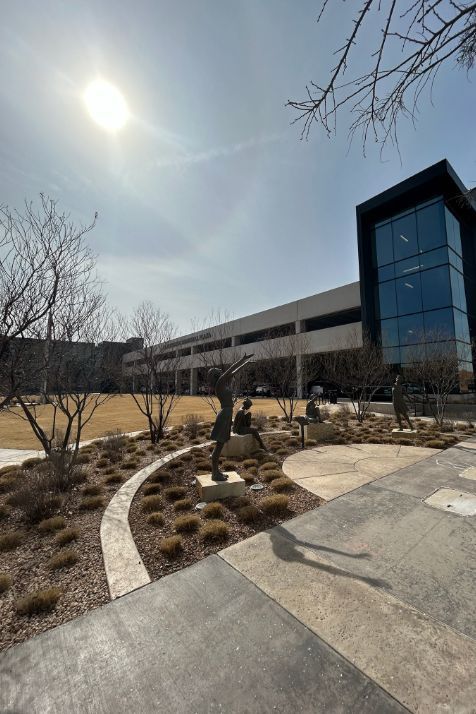 A statue of a man is standing in front of a large building.