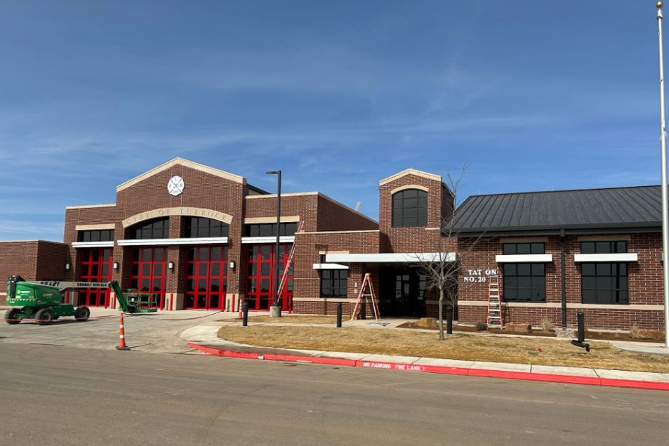A large brick building with red doors and a green tractor parked in front of it.