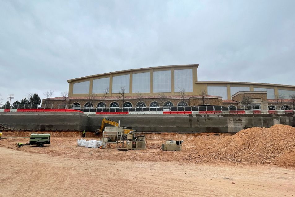 A large building is being built in a dirt field.