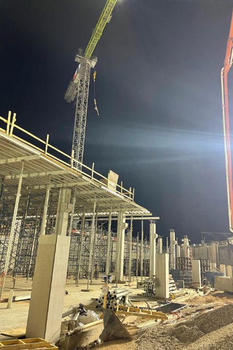A large building is being built at night with a crane in the background.
